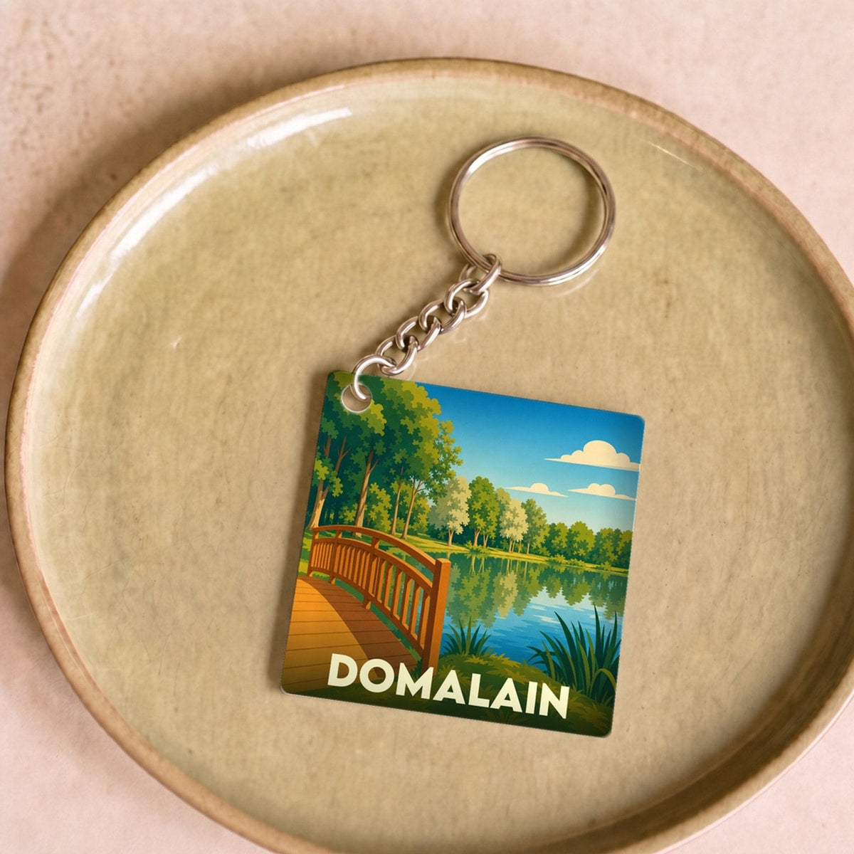 Porte-clés souvenir de la ville de Domalain avec une illustration stylisée de son étang.