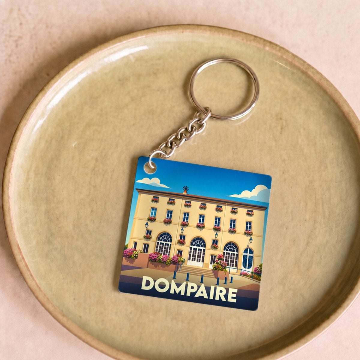 Porte-clés souvenir de la ville de Dompaire avec une illustration stylisée de son architecture.