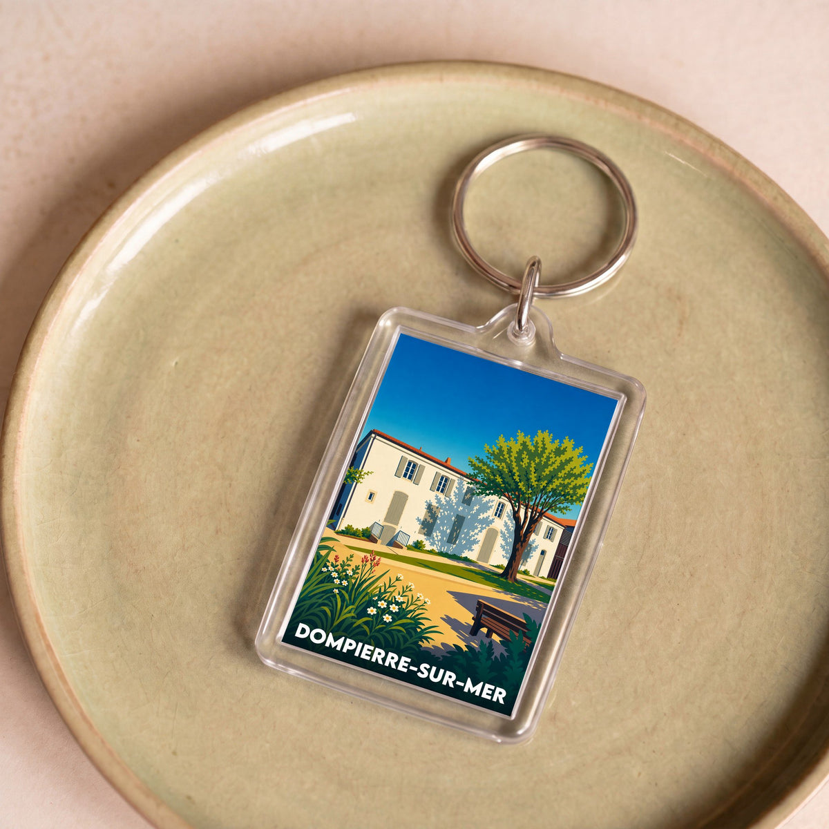 Porte-clés souvenir de la ville de Dompierre-sur-Mer avec une illustration stylisée d'une maison charentaise.
