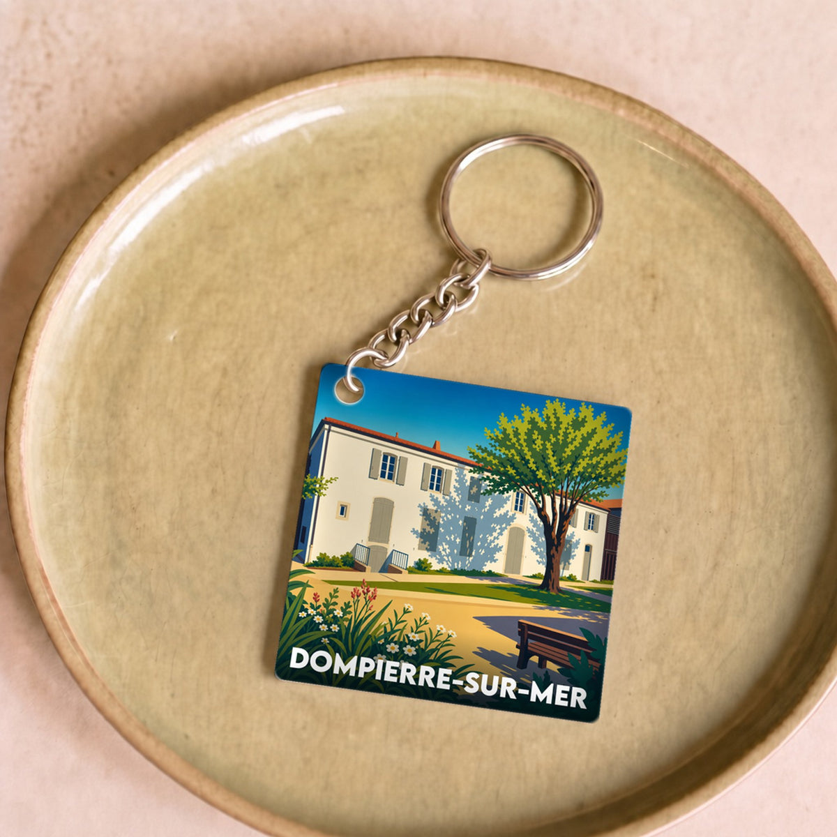 Porte-clés souvenir de la ville de Dompierre-sur-Mer avec une illustration stylisée d'une maison charentaise.