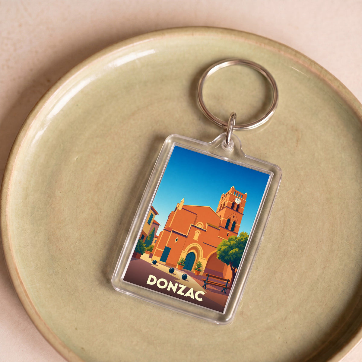 Porte-clés souvenir de la ville de Donzac avec une illustration stylisée de son église.