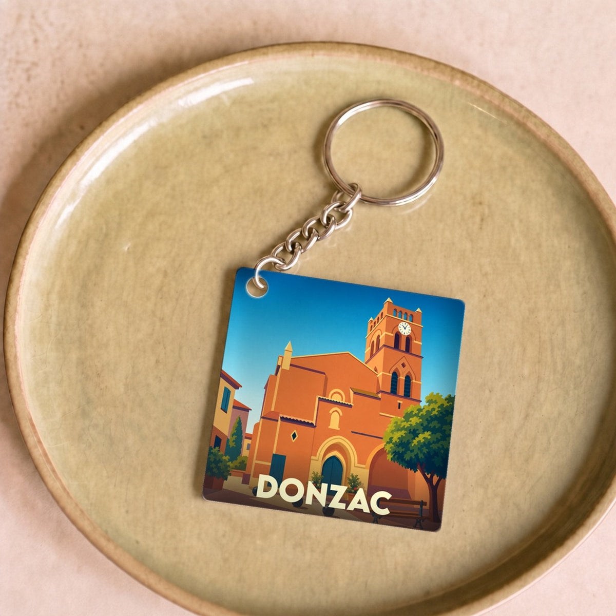 Porte-clés souvenir de la ville de Donzac avec une illustration stylisée de son église.