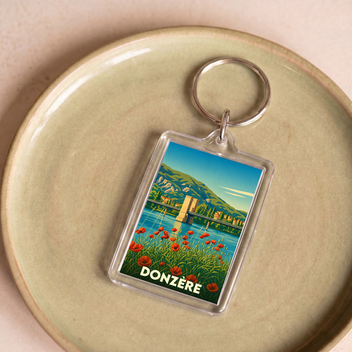 Porte-clés souvenir de la ville de Donzère avec une illustration stylisée d'un pont et de coquelicots.