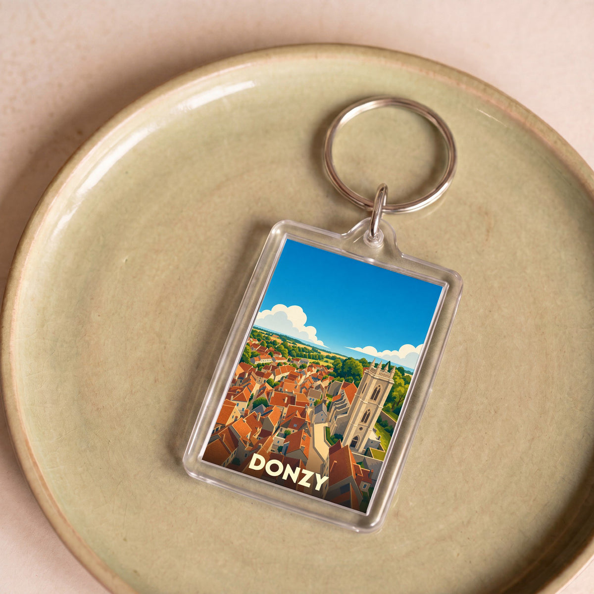 Porte-clés souvenir de la ville de Donzy avec une illustration stylisée d'un panorama urbain.