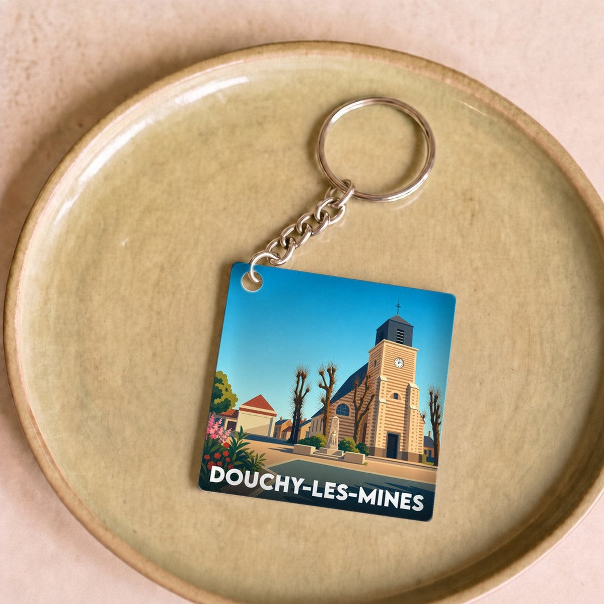 Porte-clés souvenir de la ville de Douchy-les-Mines avec une illustration stylisée de son église.