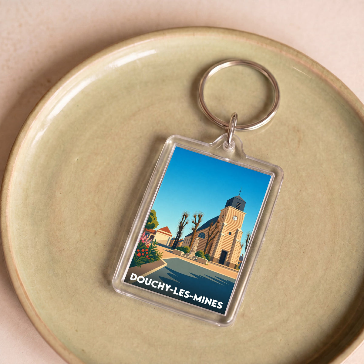 Porte-clés souvenir de la ville de Douchy-les-Mines avec une illustration stylisée de son église.