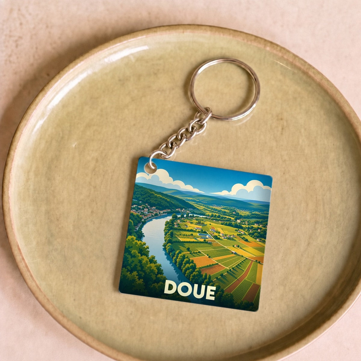 Porte-clés souvenir de la ville de Doue avec une illustration stylisée d'un paysage de vallée.