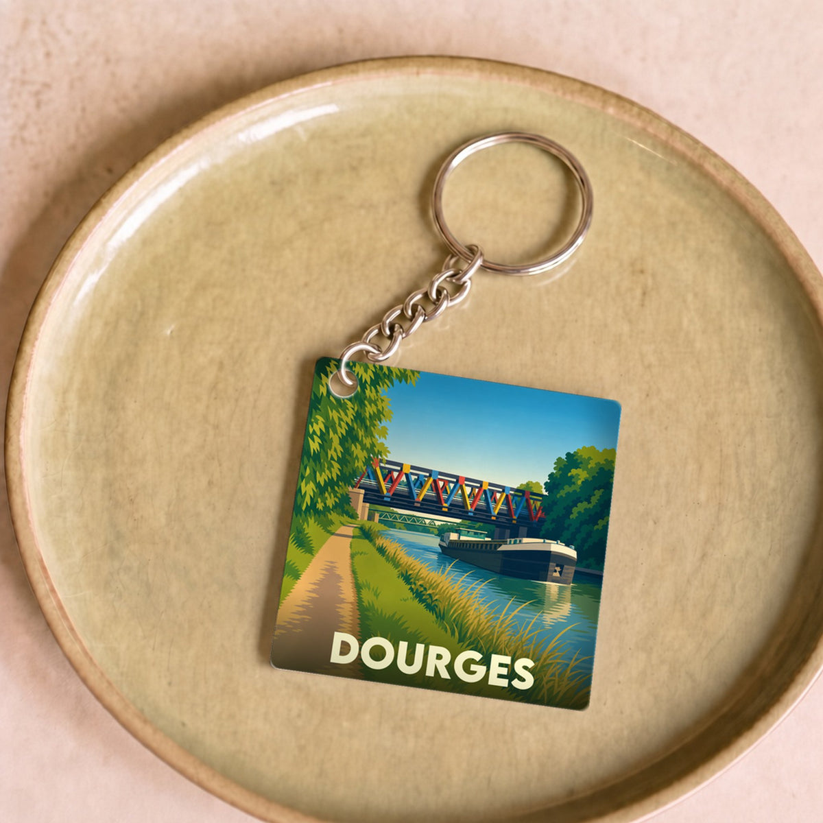Porte-clés souvenir de la ville de Dourges avec une illustration stylisée d'un canal et d'un pont.