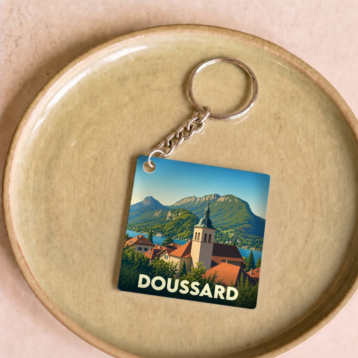 Porte-clés souvenir de la ville de Doussard avec une illustration stylisée de son église et du lac.