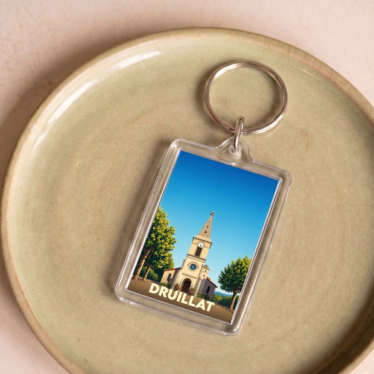 Porte-clés souvenir de la ville de Druillat avec une illustration stylisée d'une église sous un ciel bleu.