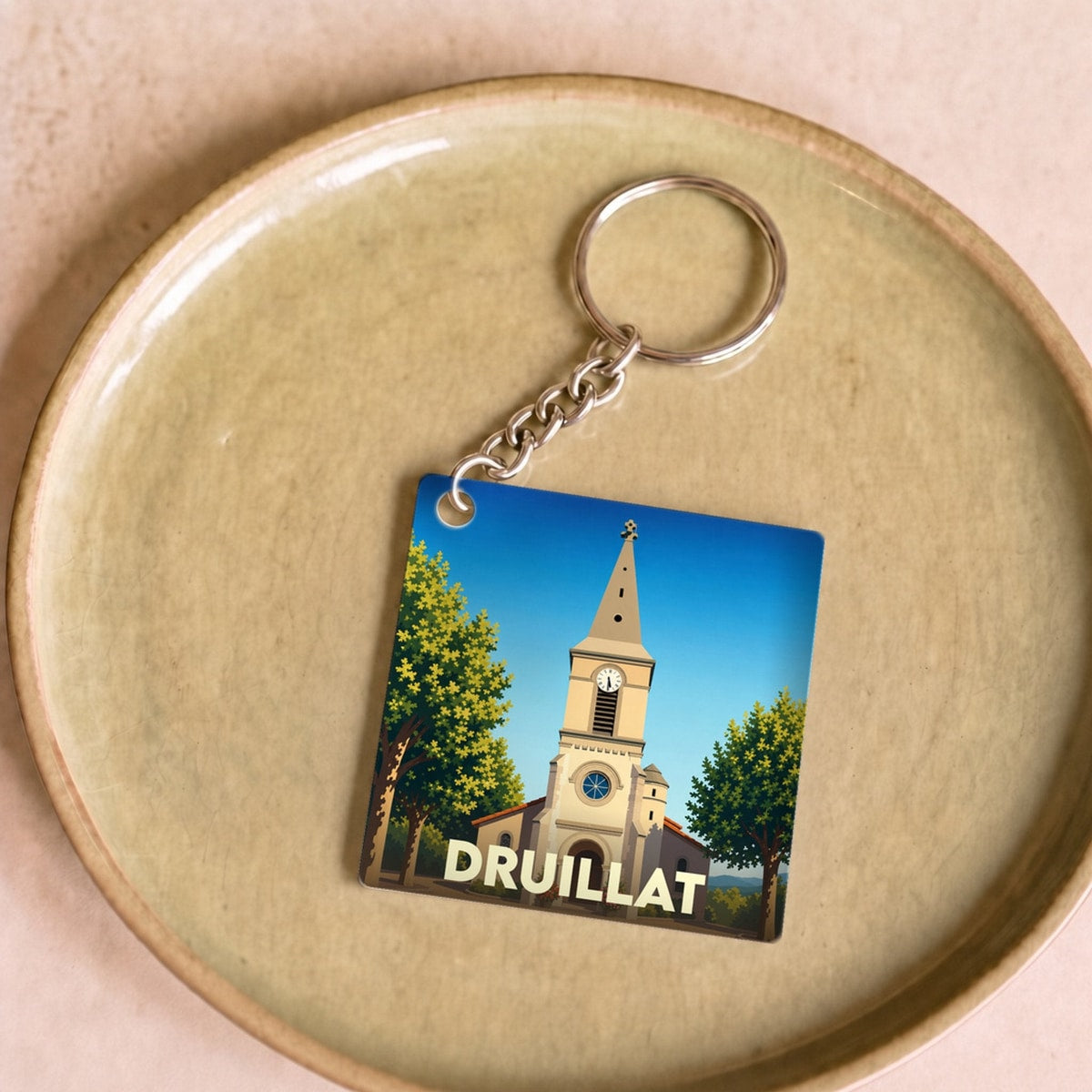 Porte-clés souvenir de la ville de Druillat avec une illustration stylisée d'une église sous un ciel bleu.