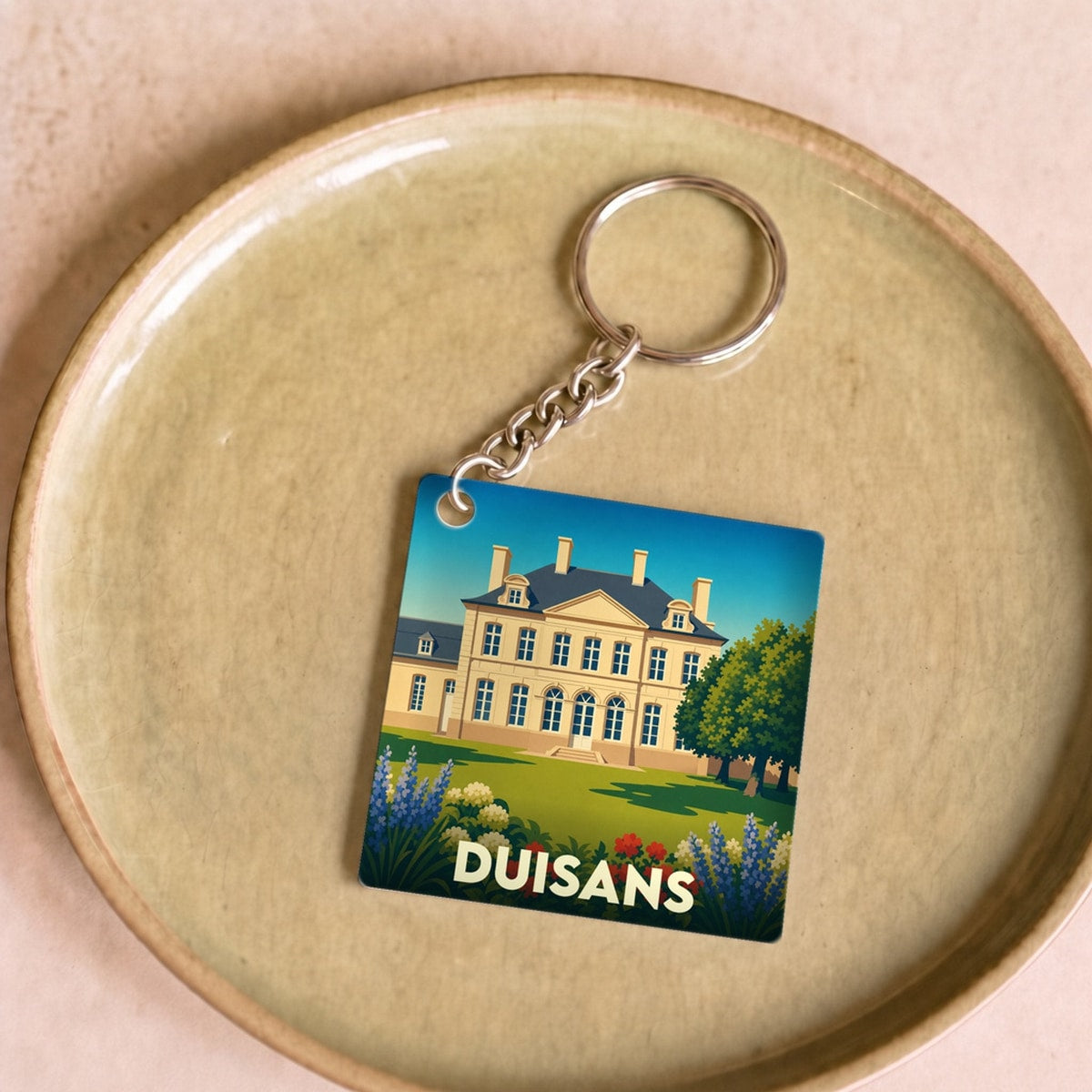 Porte-clés souvenir de la ville de Duisans avec une illustration stylisée d'un château et ses jardins.