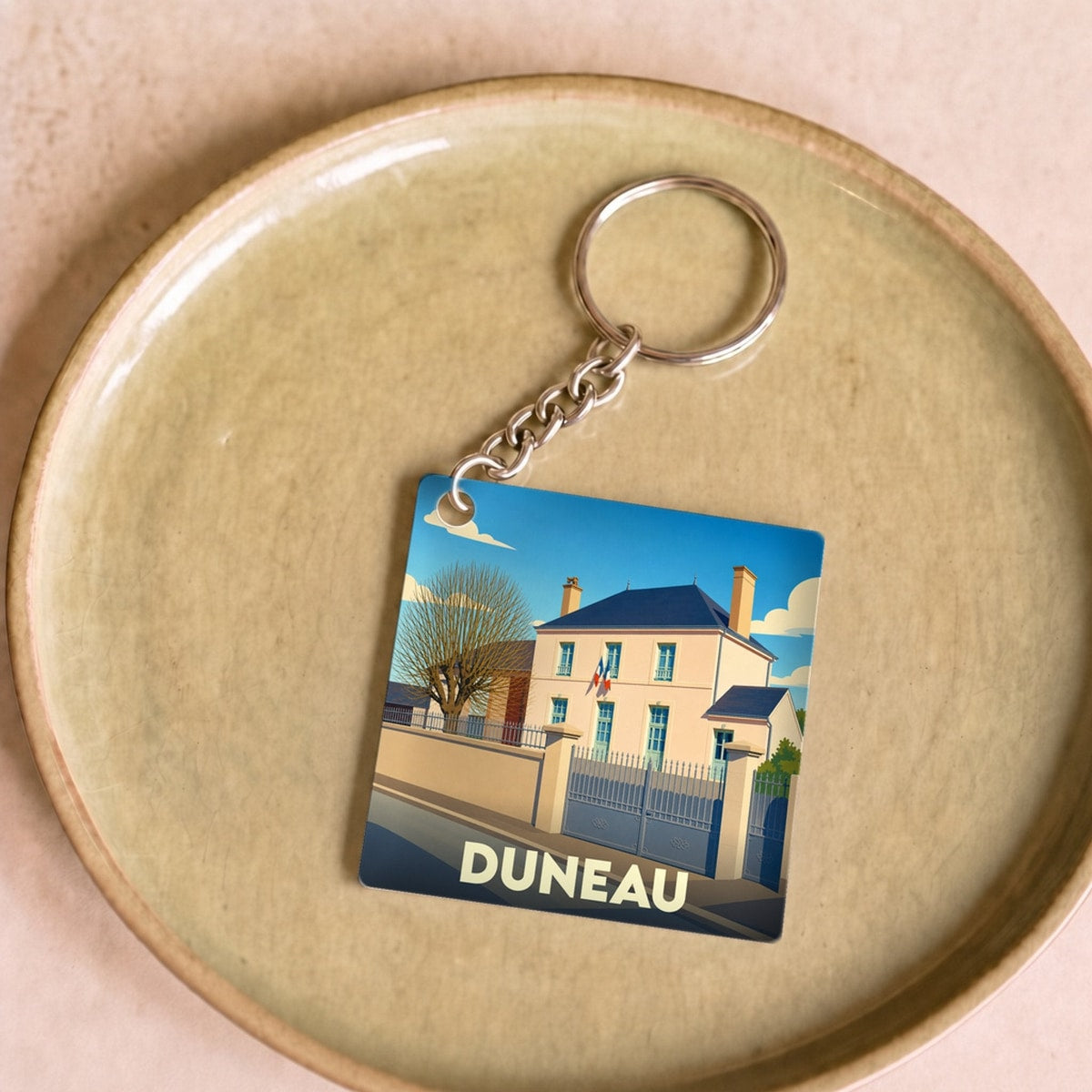 Porte-clés souvenir de la ville de Duneau avec une illustration stylisée de sa mairie.