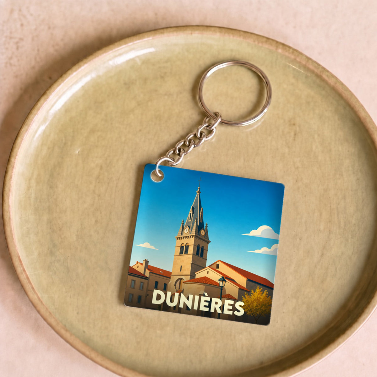 Porte-clés souvenir de la ville de Dunières avec une illustration stylisée de son église.