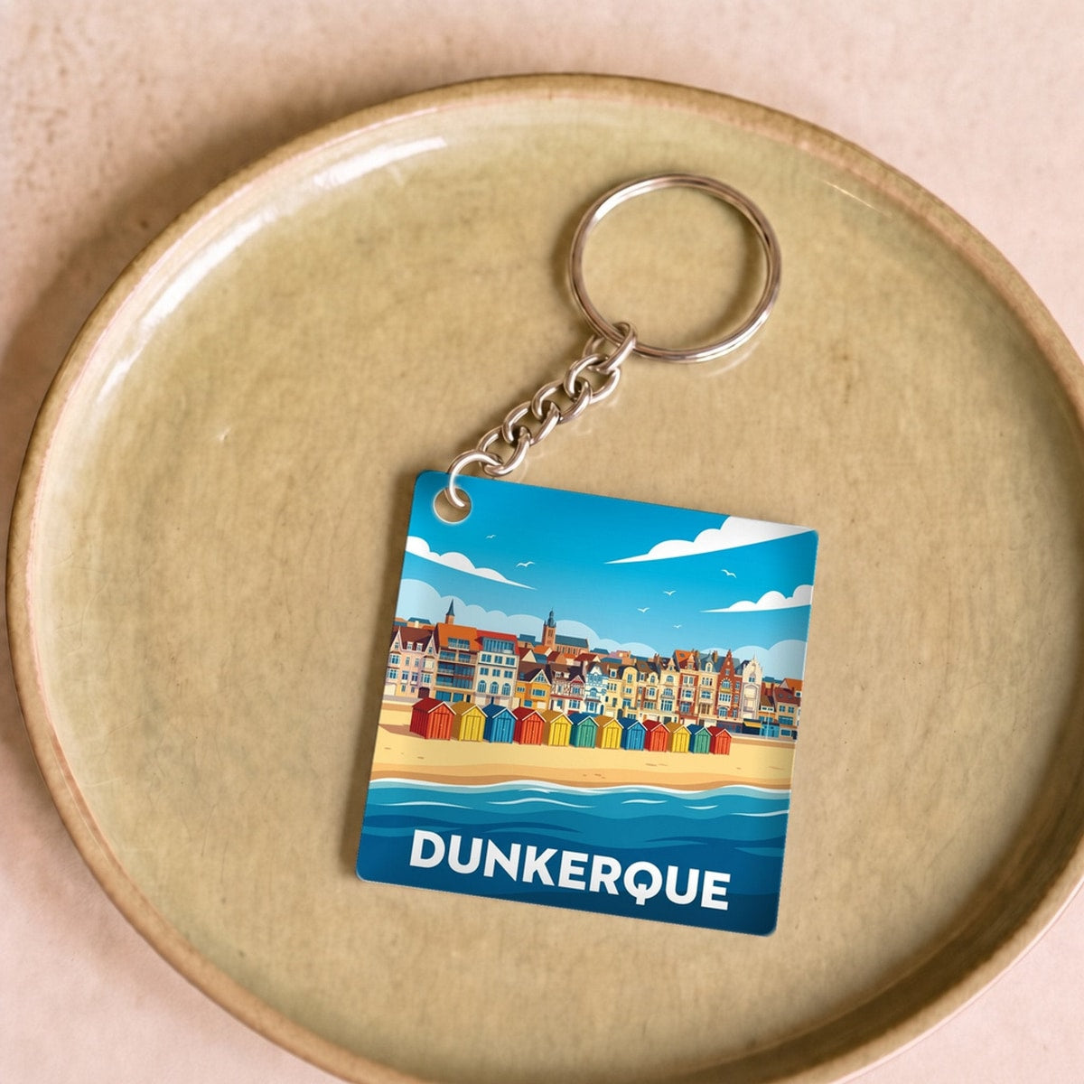 Porte-clés souvenir de la ville de Dunkerque avec une illustration stylisée de sa plage et de ses cabines colorées.