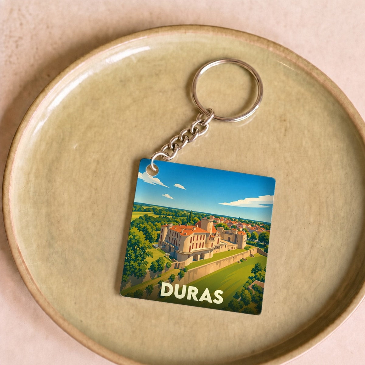 Porte-clés souvenir de la ville de Duras avec une illustration stylisée de son château.