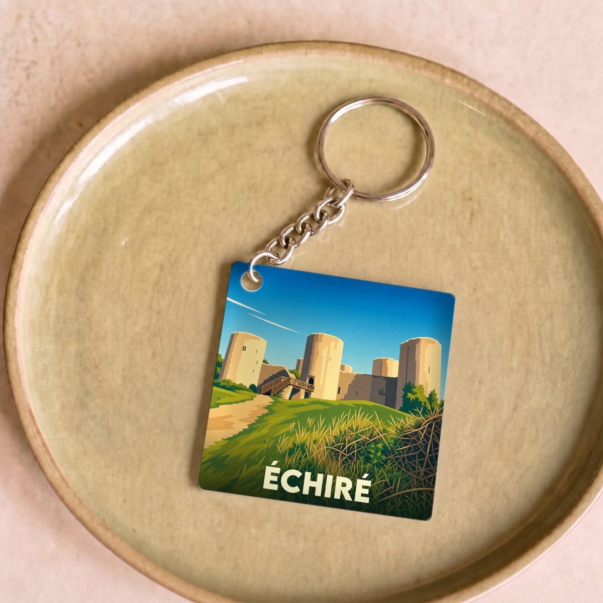 Porte-clés souvenir de la ville de Échiré avec une illustration stylisée de son château.