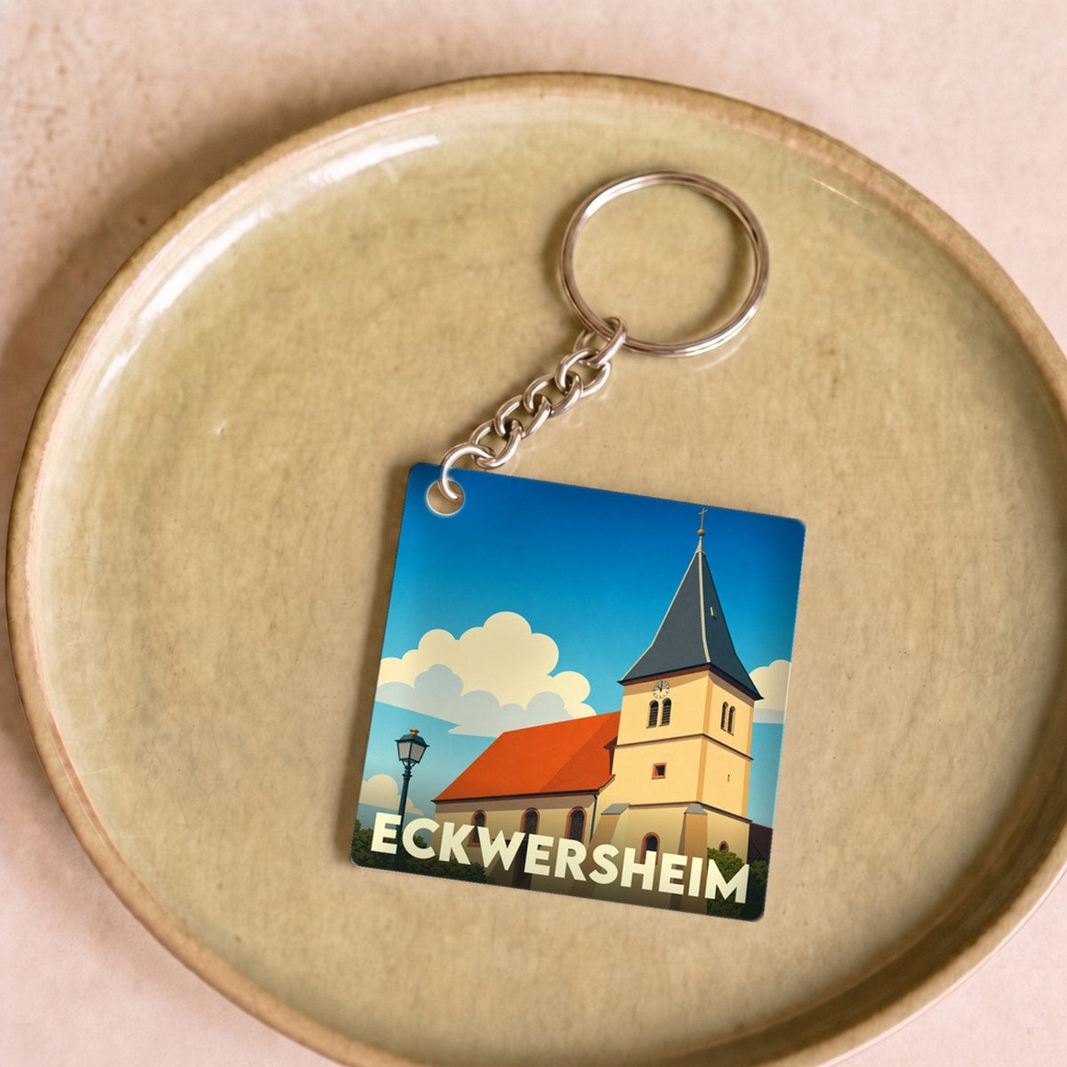 Porte-clés souvenir de la ville de Eckwersheim avec une illustration stylisée de son église sous un ciel bleu.
