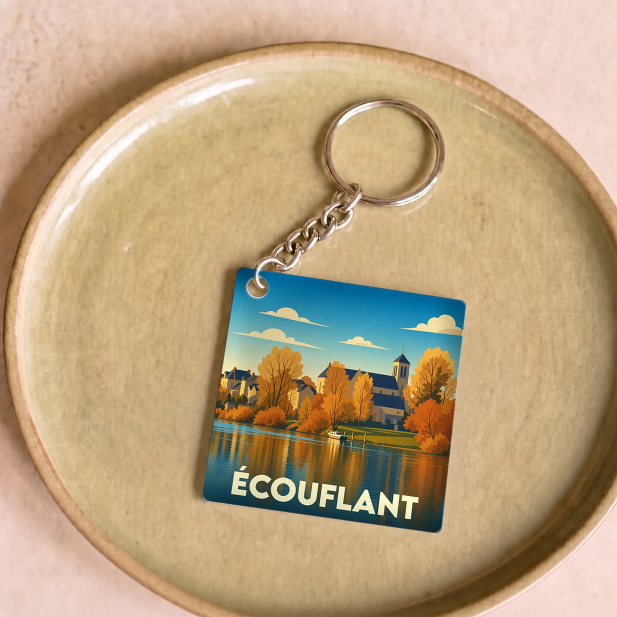 Porte-clés souvenir de la ville d'Écouflant avec une illustration stylisée de ses bords de rivière en automne.