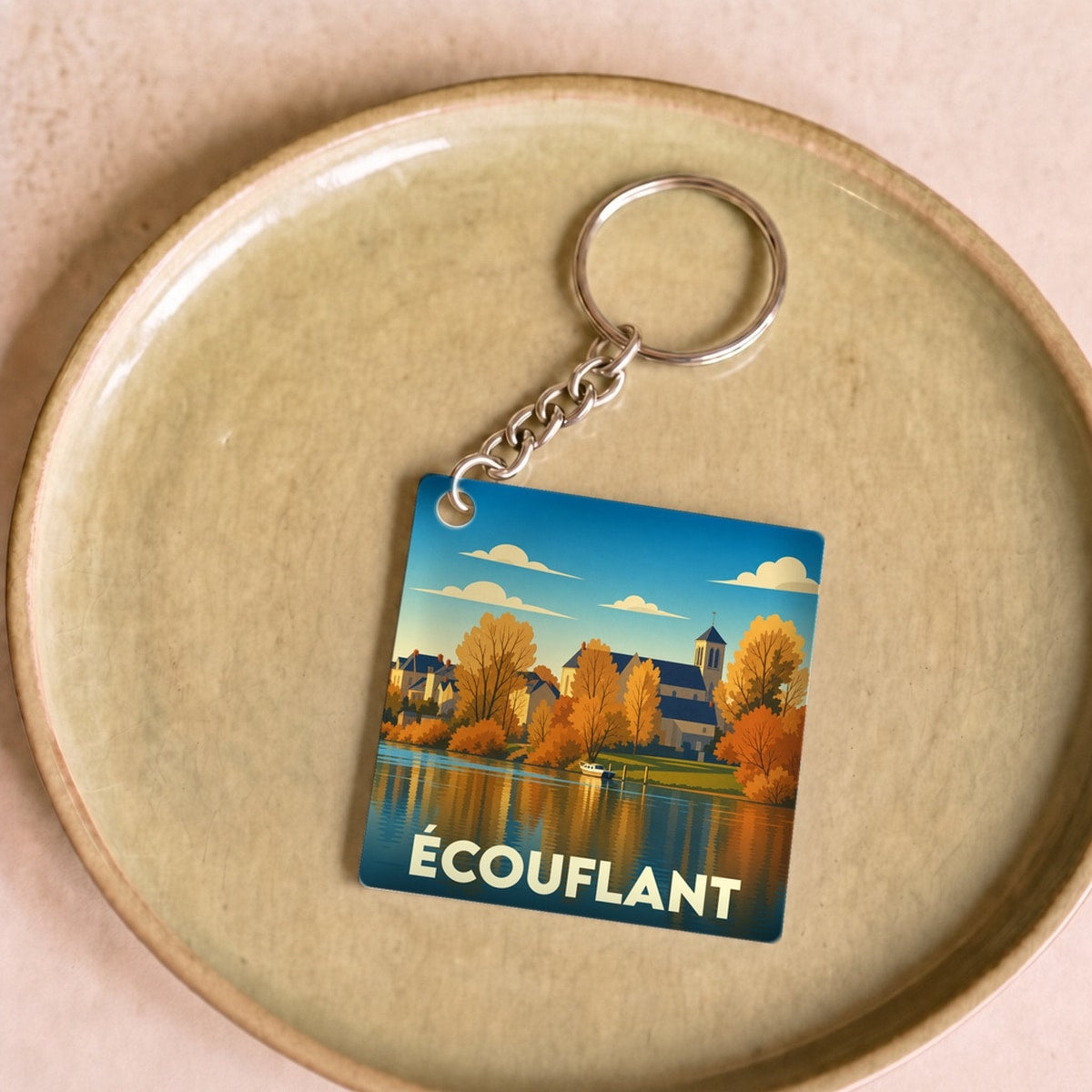 Porte-clés souvenir de la ville d'Écouflant avec une illustration stylisée de ses bords de rivière en automne.