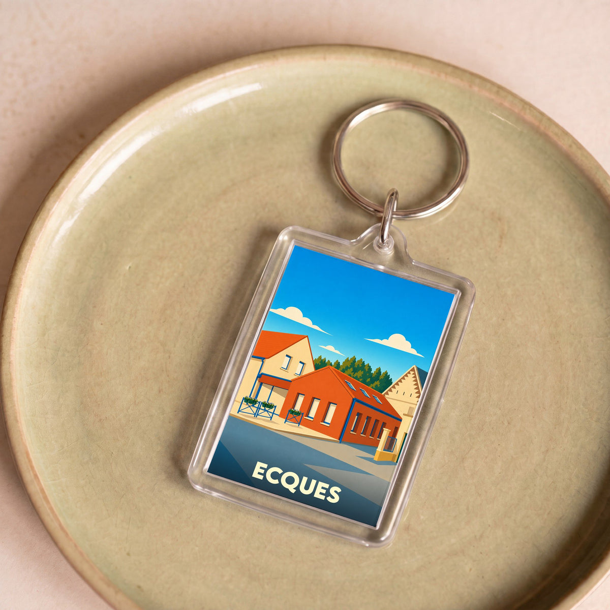 Porte-clés souvenir de la ville d'Ecques avec une illustration stylisée de bâtiments locaux.