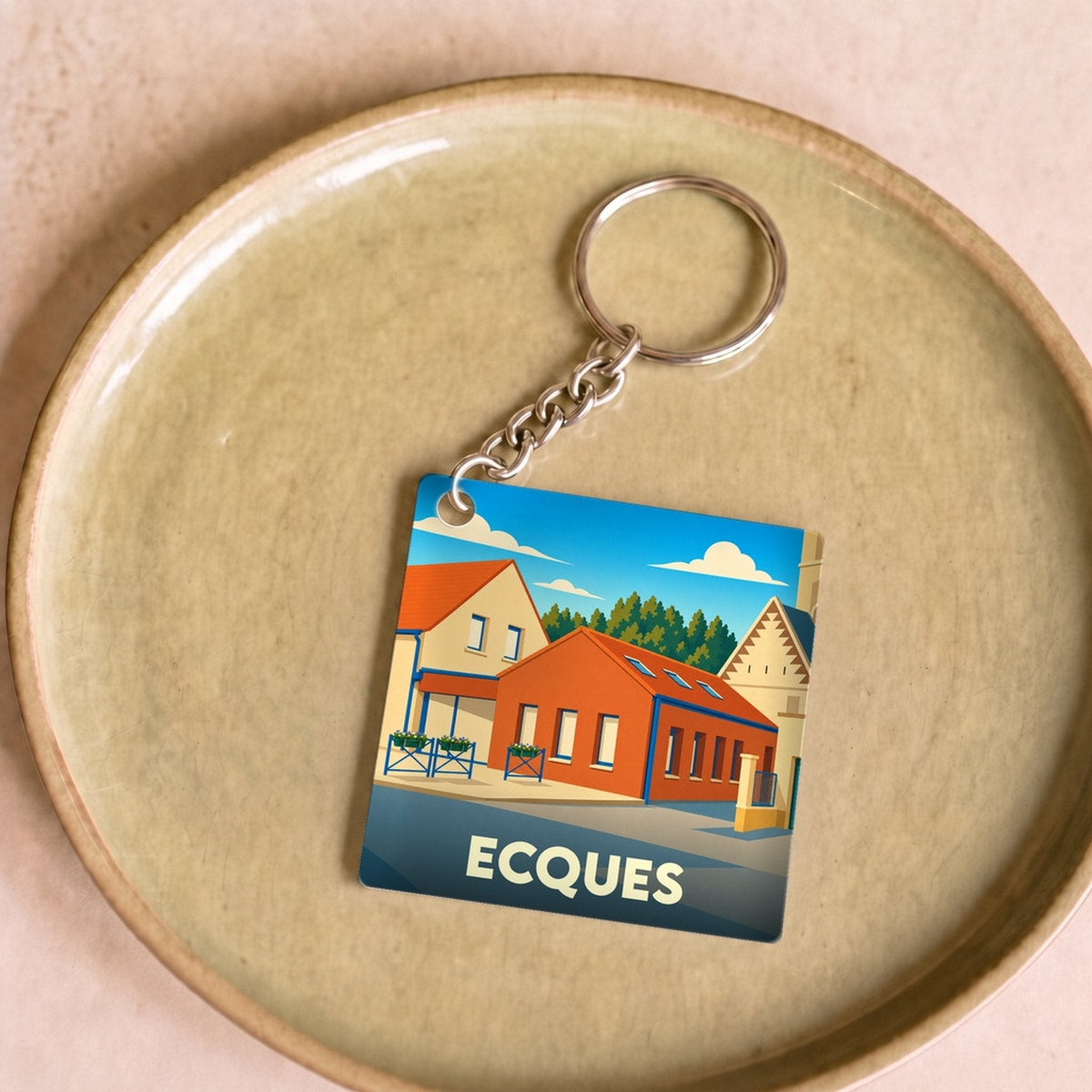 Porte-clés souvenir de la ville d'Ecques avec une illustration stylisée de bâtiments locaux.