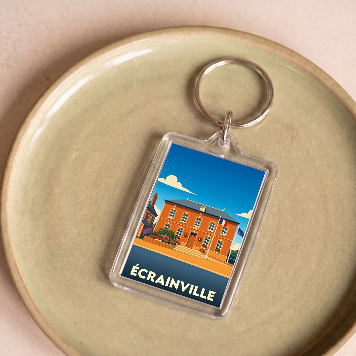 Porte-clés souvenir de la ville d'Écrainville avec une illustration stylisée de sa mairie.
