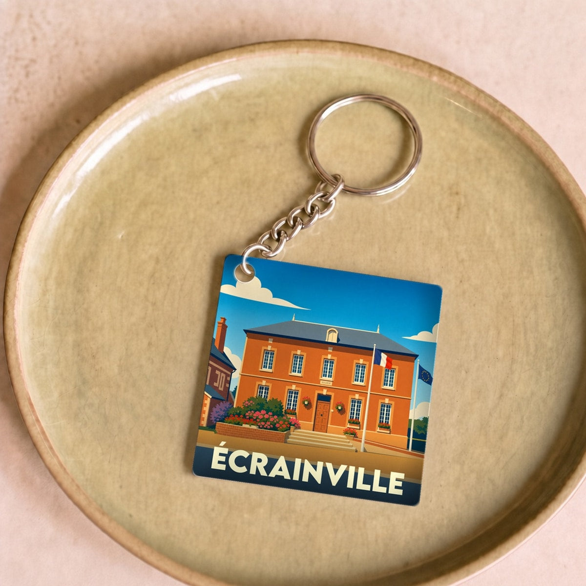 Porte-clés souvenir de la ville d'Écrainville avec une illustration stylisée de sa mairie.