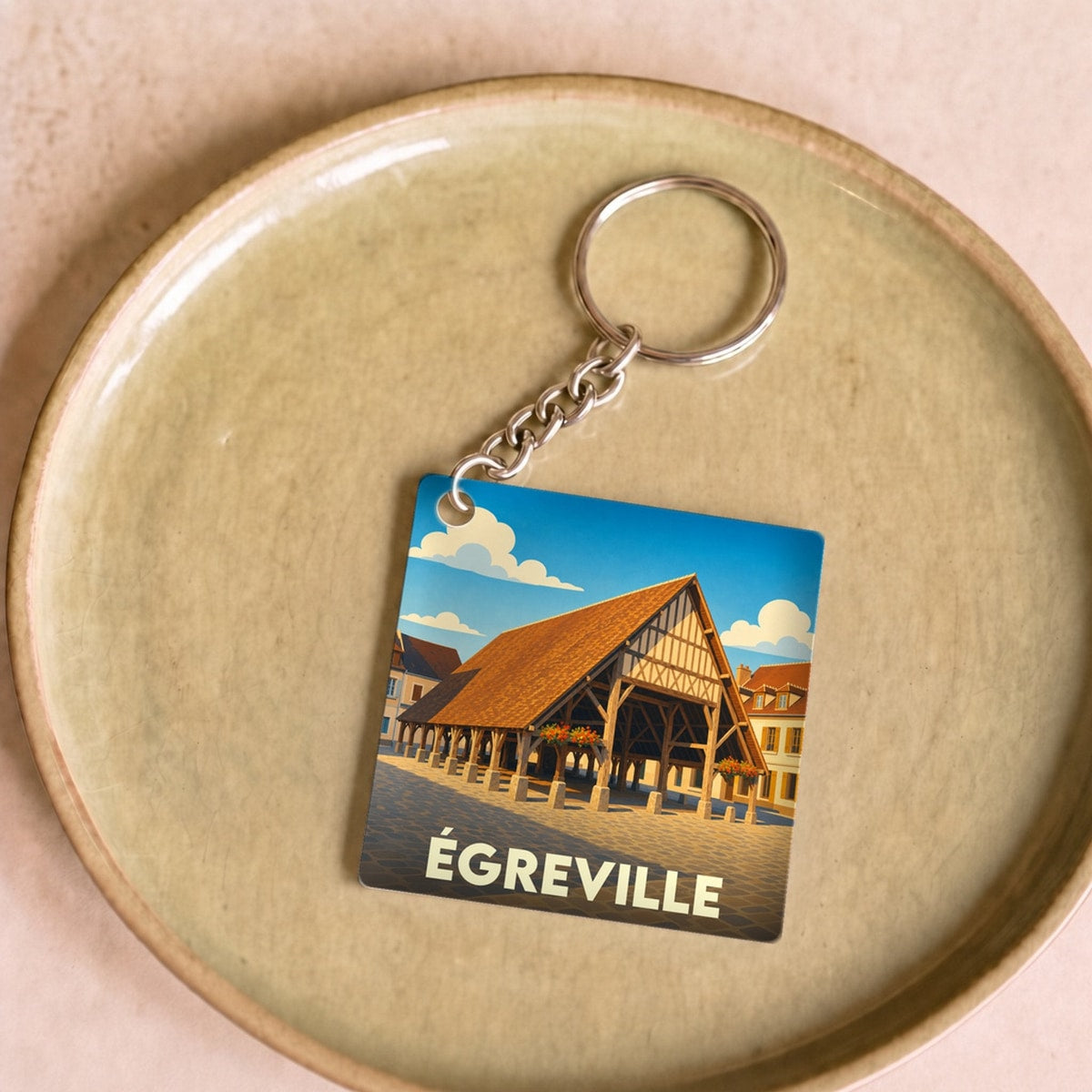 Porte-clés souvenir de la ville de Égreville avec une illustration stylisée de ses halles historiques.
