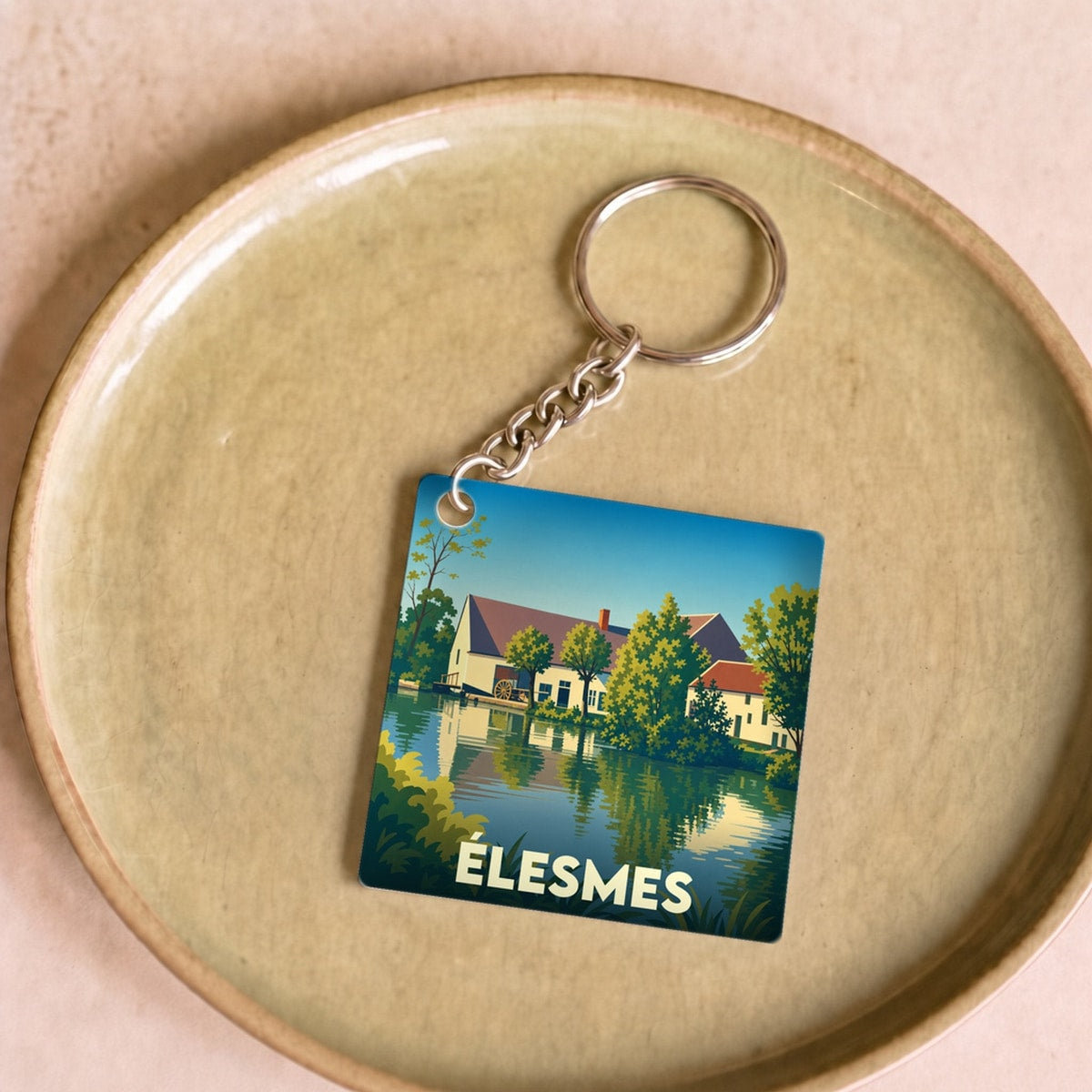 Porte-clés souvenir de la ville de Élesmes avec une illustration stylisée d'un paysage au bord de l'eau.