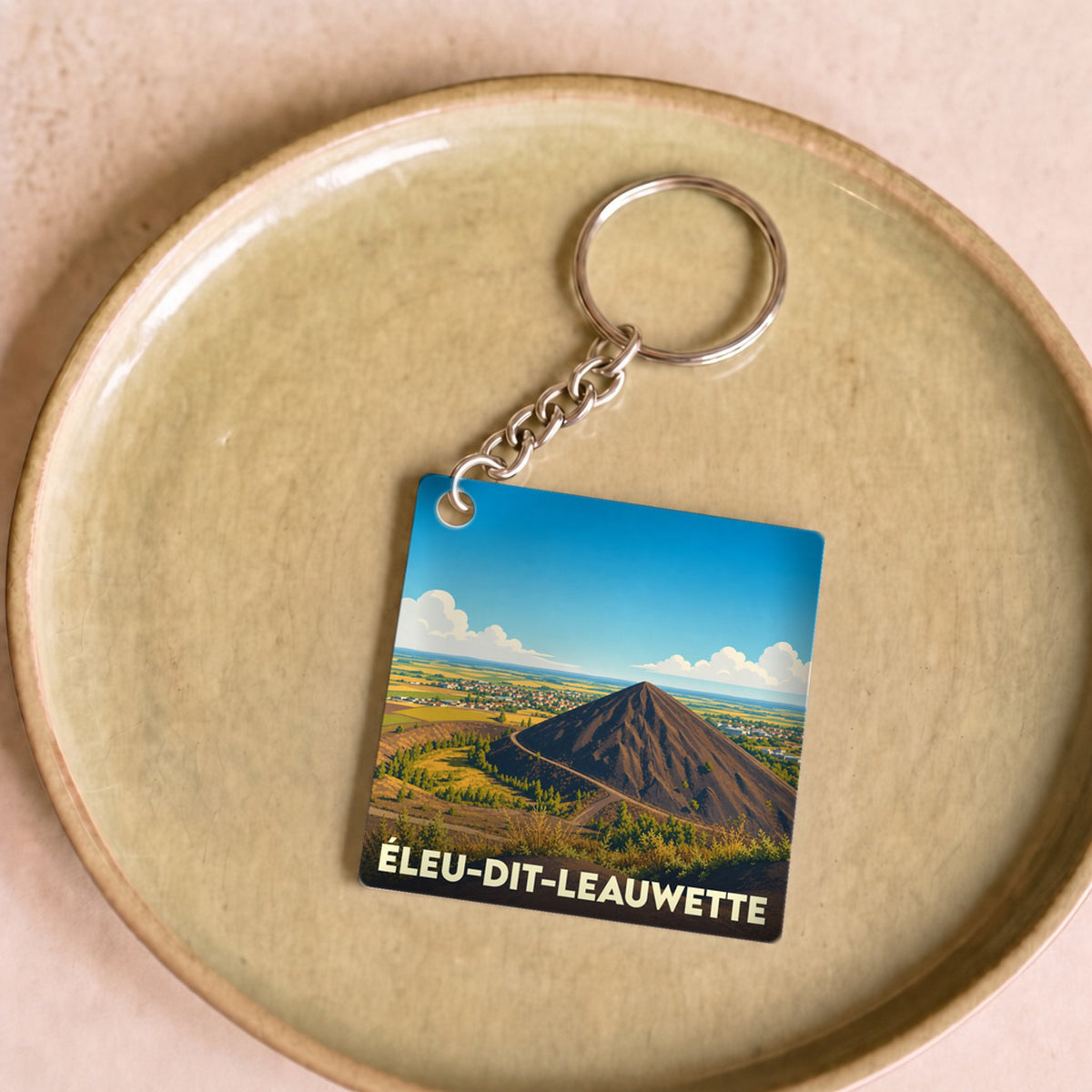 Porte-clés souvenir de la ville d’Éleu-dit-Leauwette avec une illustration stylisée.