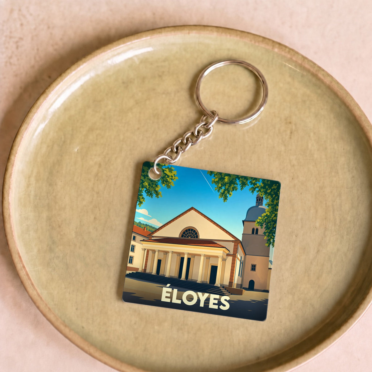 Porte-clés souvenir de la ville d'Éloyes avec une illustration stylisée.