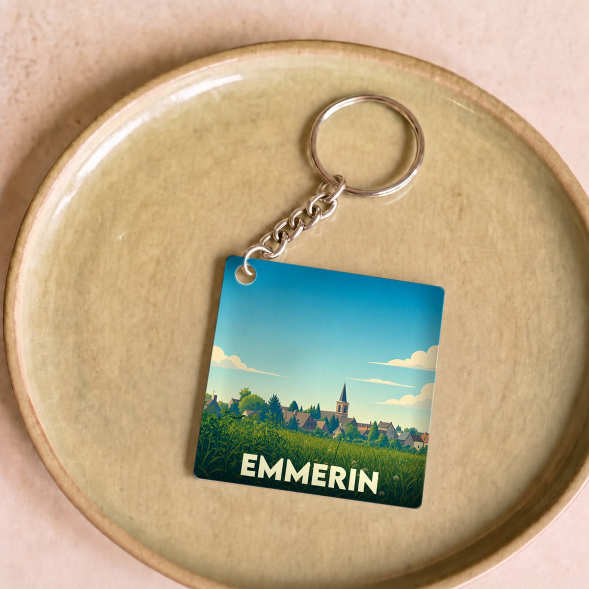 Porte-clés souvenir de la ville d'Emmerin avec une illustration stylisée de son paysage champêtre.