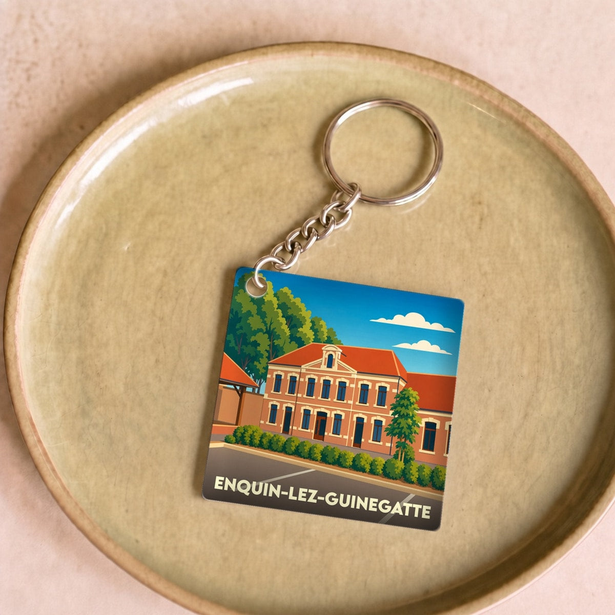 Porte-clés souvenir de la ville d'Enquin-lez-Guinegatte avec une illustration stylisée.