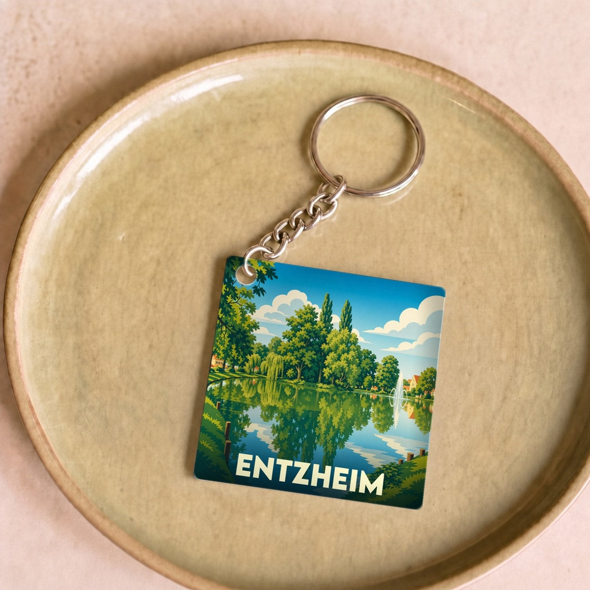 Porte-clés souvenir de la ville d'Entzheim avec une illustration stylisée d'un paysage lacustre.