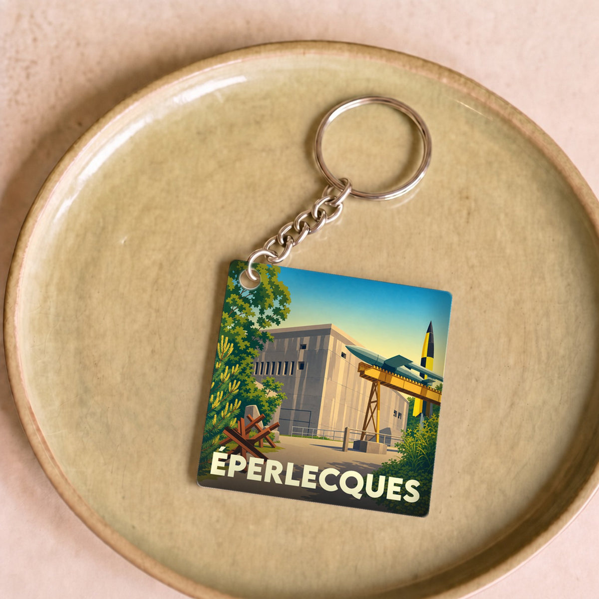 Porte-clés souvenir de la ville d'Éperlecques avec une illustration stylisée d'un blockhaus et de fusées.