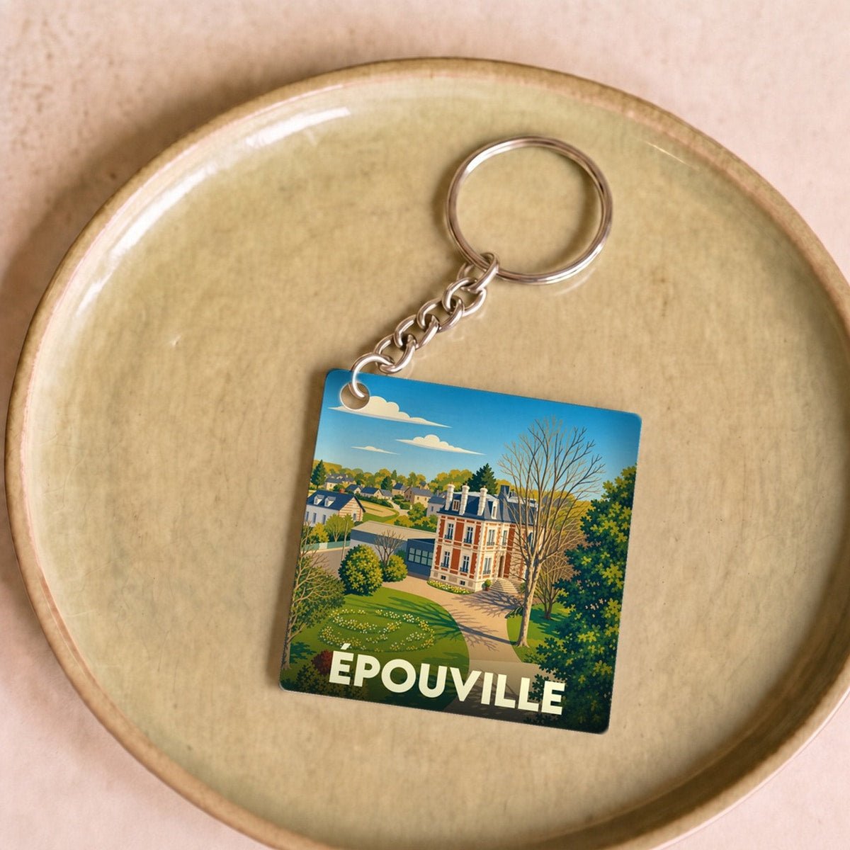 Porte-clés souvenir de la ville d'Épouville avec une illustration stylisée d'un manoir et son parc.