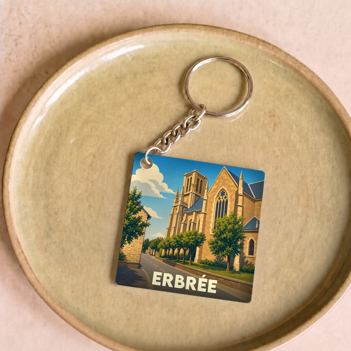 Porte-clés souvenir de la ville d'Erbrée avec une illustration stylisée de son église sous un ciel bleu.
