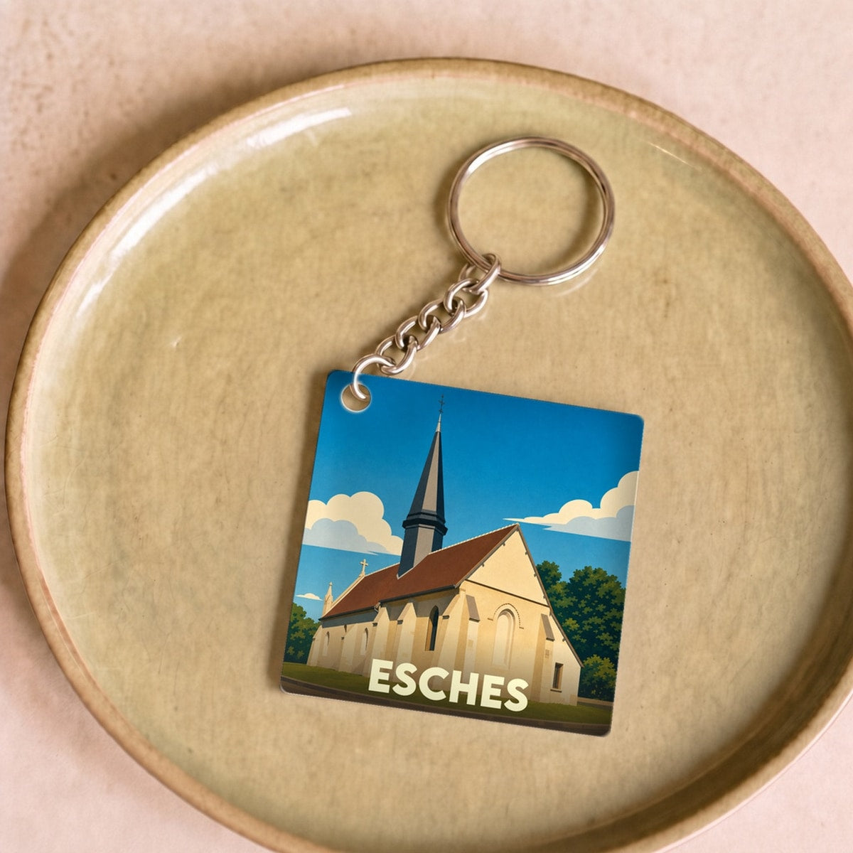 Porte-clés souvenir de la ville d'Esches avec une illustration stylisée de son église.