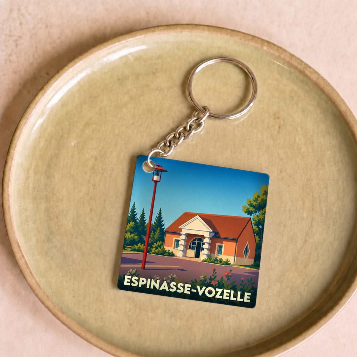 Porte-clés souvenir de la ville d'Espinasse-Vozelle avec une illustration stylisée.