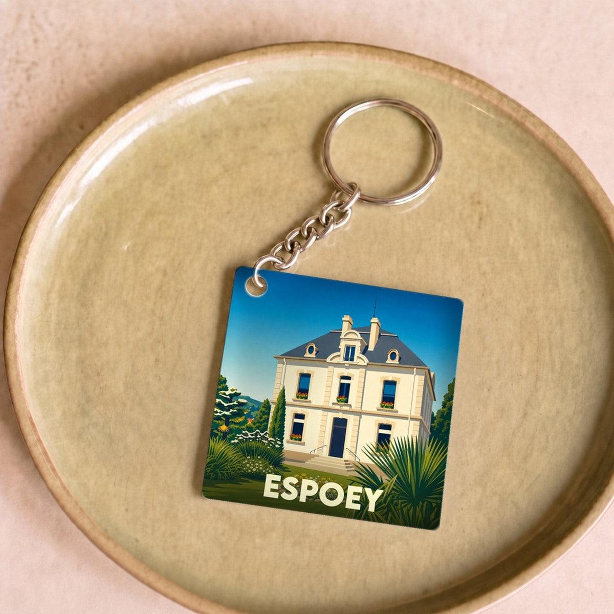 Porte-clés souvenir de la ville de Espoey avec une illustration stylisée d'une maison de maître.