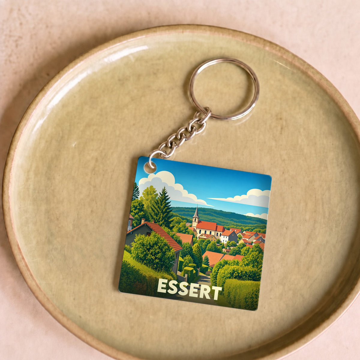 Porte-clés souvenir de la ville d'Essert avec une illustration stylisée d'un village verdoyant.