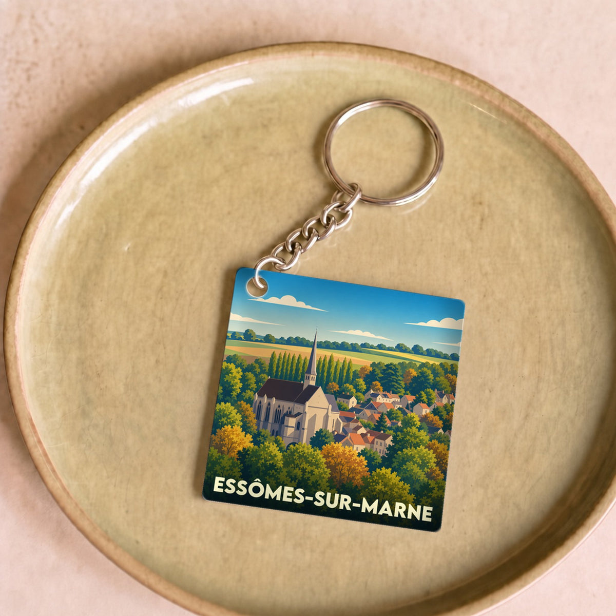 Porte-clés souvenir de la ville d'Essômes-sur-Marne avec une illustration stylisée de son église et de son paysage.