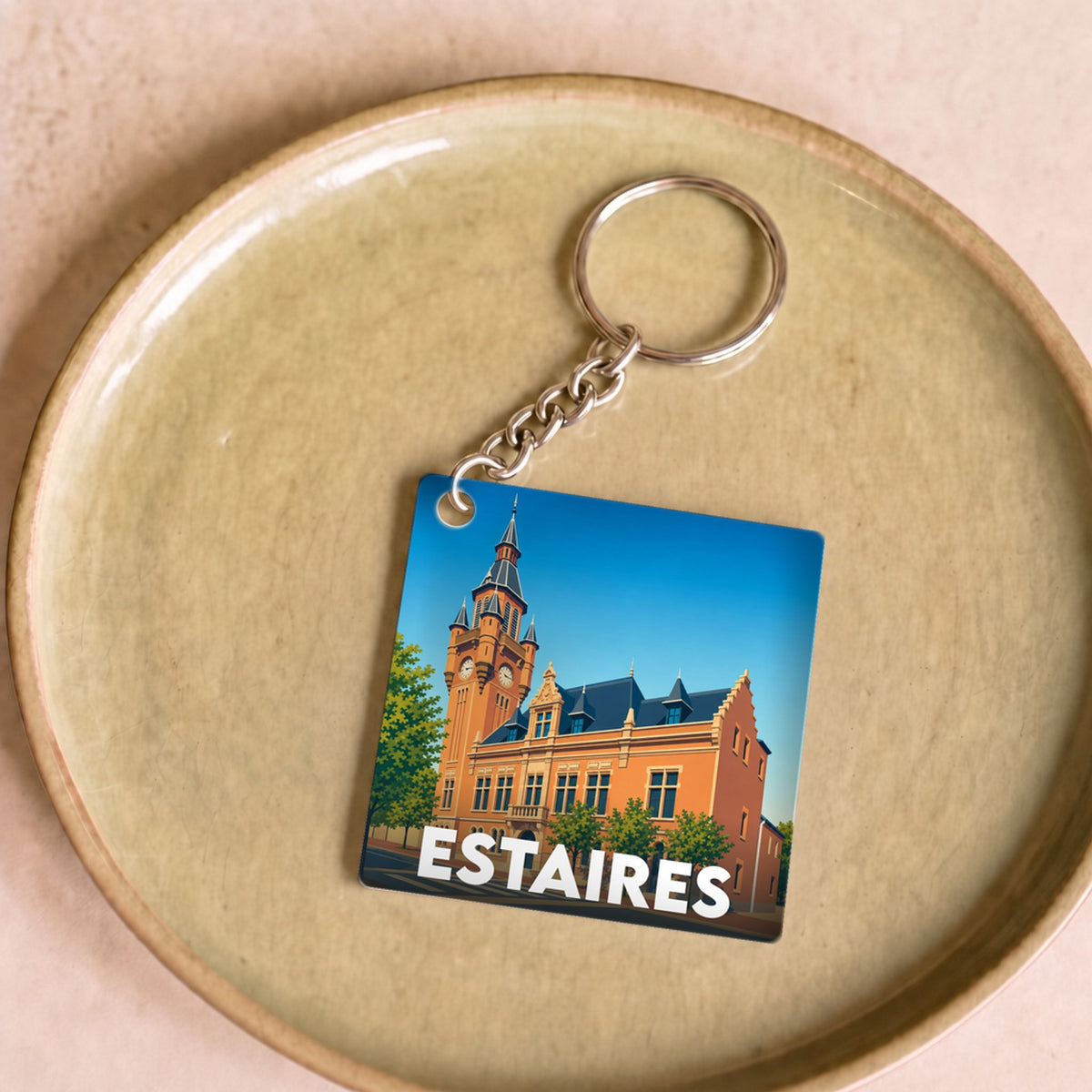 Porte-clés souvenir de la ville d'Estaires avec une illustration stylisée de son hôtel de ville.