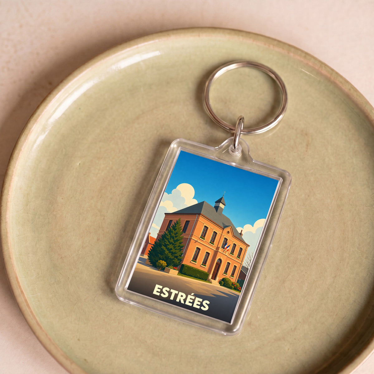 Porte-clés souvenir de la ville d'Estrées avec une illustration stylisée de sa mairie.