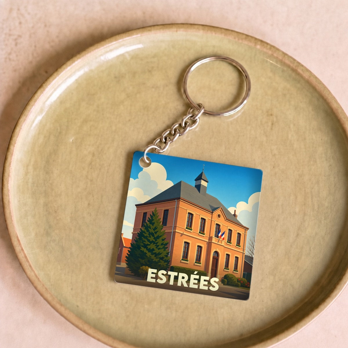 Porte-clés souvenir de la ville d'Estrées avec une illustration stylisée de sa mairie.