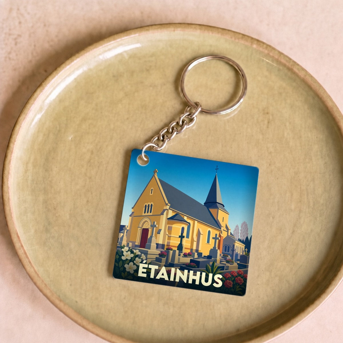 Porte-clés souvenir de la ville d'Étainhus avec une illustration stylisée de son église et de son cimetière.