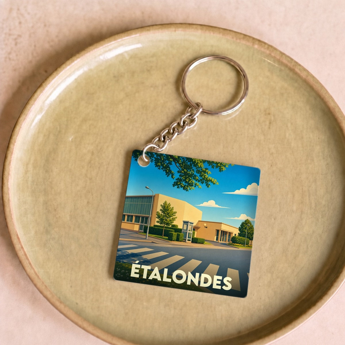 Porte-clés souvenir de la ville d'Étalondes avec une illustration stylisée d'un paysage urbain.