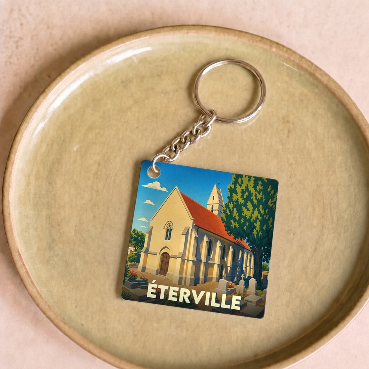 Porte-clés souvenir de la ville de Éterville avec une illustration stylisée de son église.