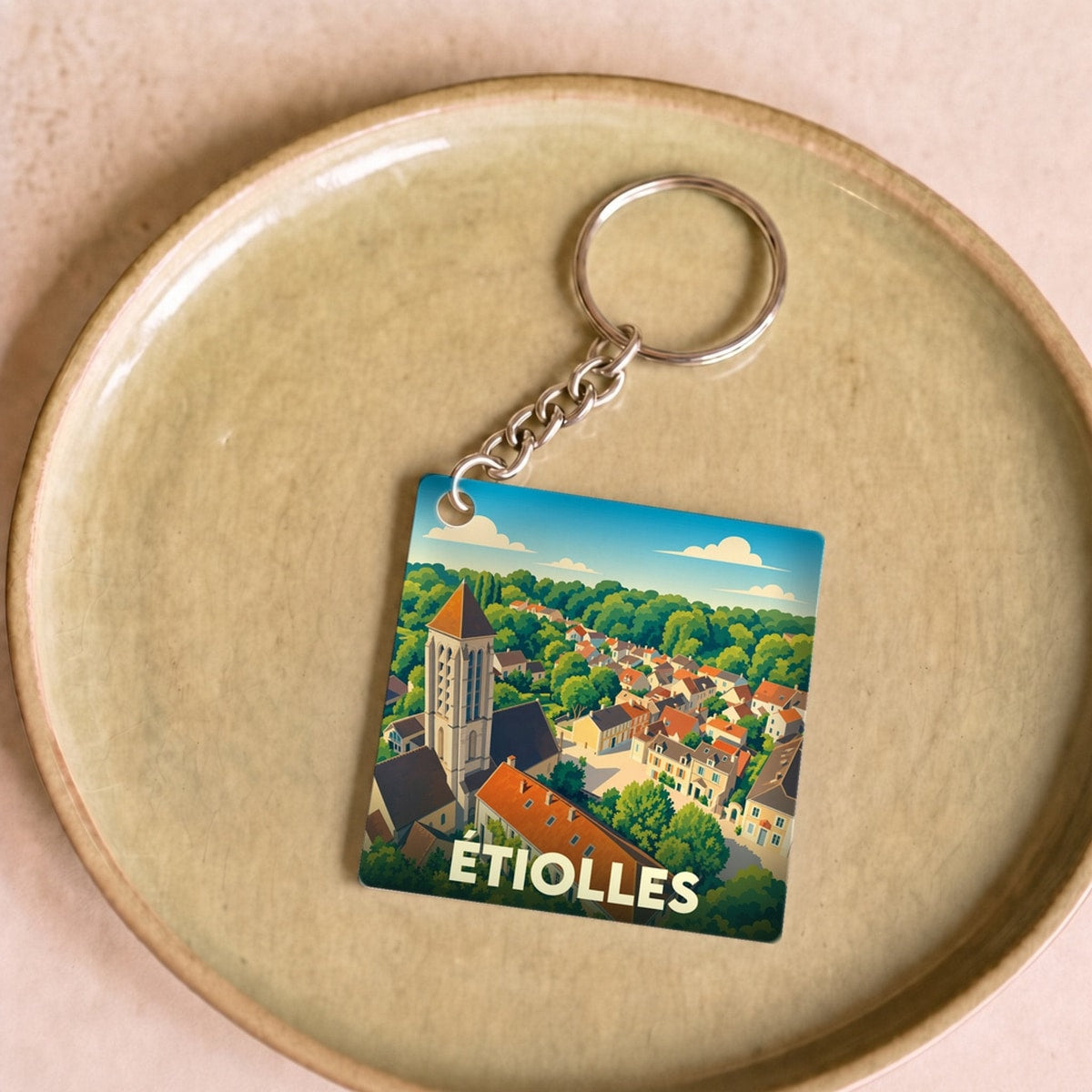 Porte-clés souvenir de la ville de Étiolles avec une illustration stylisée d'un paysage urbain.